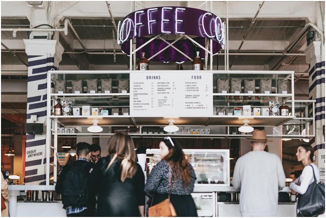 A group gathered inside a coffee shop, engaged in conversation, and showcased a productive customer reference program.